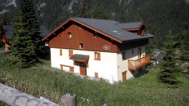 A chalet-style building with a sloped roof, wooden exterior, and a balcony.