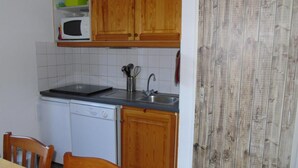 A compact kitchen with wooden cabinets, a microwave, a dishwasher, and a sink.