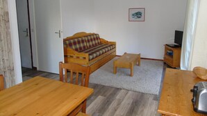 A cozy living room with a wooden sofa, a coffee table, and a dining table.