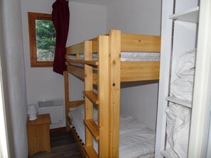 A bunk bed room with a window, a heater, and a small wooden table. - 1st floor, view mountain, balcony, tv, ski locker, 36m², Valfréjus (Valfréjus)