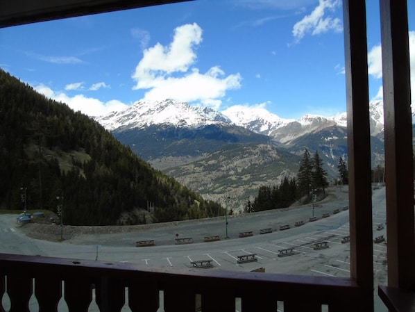 A parking area with picnic tables and a view of snow-capped mountains.