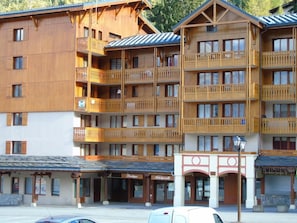 A multi-story wooden building with balconies, a sign for 'Boutique', and a 'Restaurant' sign.