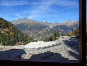 A parking lot with a view of mountains, a pile of gravel, and a few cars.