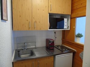 Keittiössä on puukuvioiset kaapit, ruostumattomasta teräksestä valmistettu pesuallas, mikroaaltouuni ja punainen kahvinkeitin.