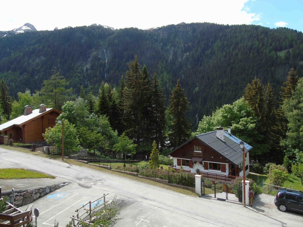 A lodge with a wooden exterior, a paved driveway, and a mountain backdrop.