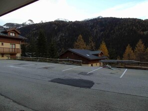 A parking lot with a building in the background, surrounded by trees and mountains.