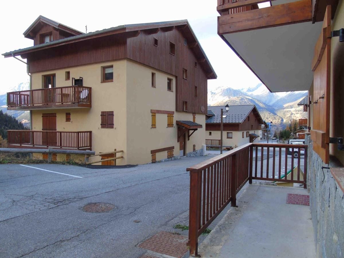 A multi-story building with wooden balconies and a mountain view.