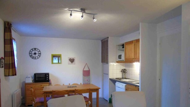 Ett kompakt bostadsutrymme med en matplats, ett kök och två stolar med hjärtformade kuddar.