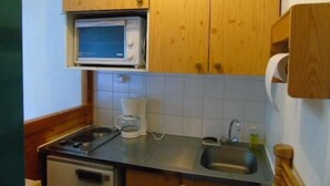 Uma cozinha compacta com armários de madeira, micro-ondas, máquina de café e pia.