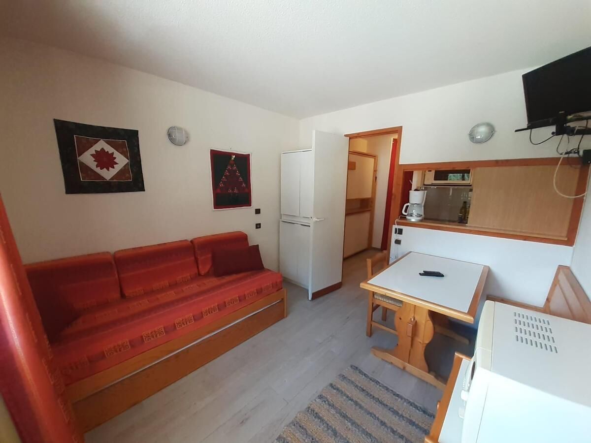 Ett kompakt bostadsutrymme med en soffa, ett litet bord, ett kylskåp och en mikrovågsugn.