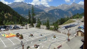 A parking lot with cars and a small building, surrounded by mountains and trees. - 3rd floor, view valley, balcony, tv, ski locker, 19m², Valfréjus (Valfréjus)