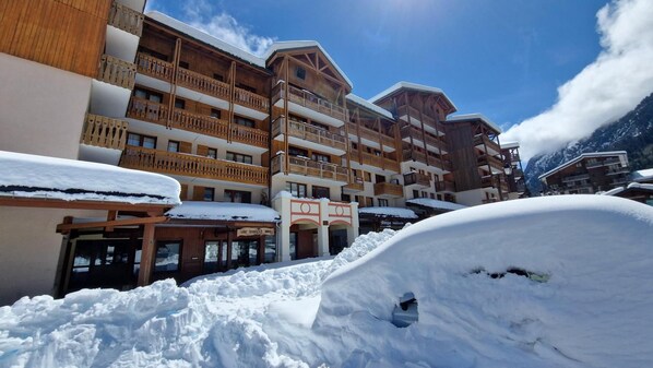 A snow-covered hotel with multiple balconies and a sign for 'Low Services Timing'.