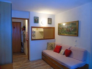 A room with a sofa, a mirror, and a painting on the wall.