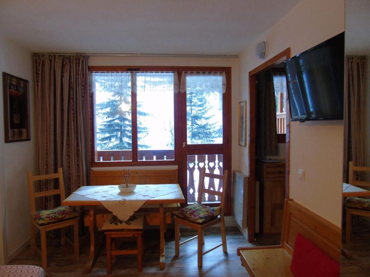 A dining area with a table, chairs, and a window with a view of trees.