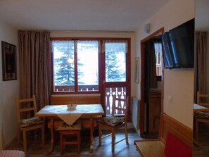 A dining area with a table, chairs, and a window with a view of trees.