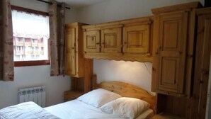 Ein Schlafzimmer mit einem hölzernen Kopfteil, einem Einzelbett und eingebauten Holzschränken darüber.