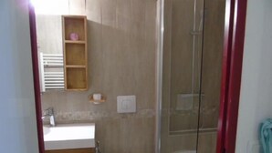 Ein Badezimmer mit Dusche, Toilette und einem Holzschrank über dem Waschbecken.