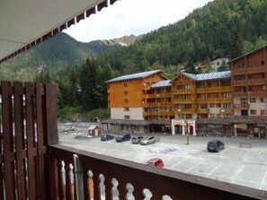 A hotel with multiple wooden buildings, a parking lot, and a mountainous backdrop.