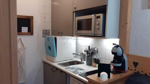A compact kitchen with a microwave, coffee machine, and a sink. - 50m from ski lifts, 2nd floor, balcony, tv, ski locker, 19m², Valfréjus (Valfréjus)