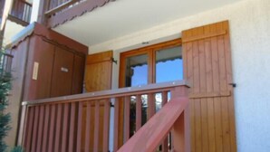 A wooden balcony with a metal railing, a wooden door, and a window with a view of the sky. - Ground floor, view valley, balcony, tv, ski locker, 33m², Valfréjus (Valfréjus)