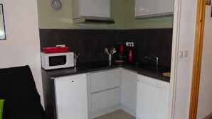 Una cucina compatta con mobili bianchi, un forno a microonde e un lavello.