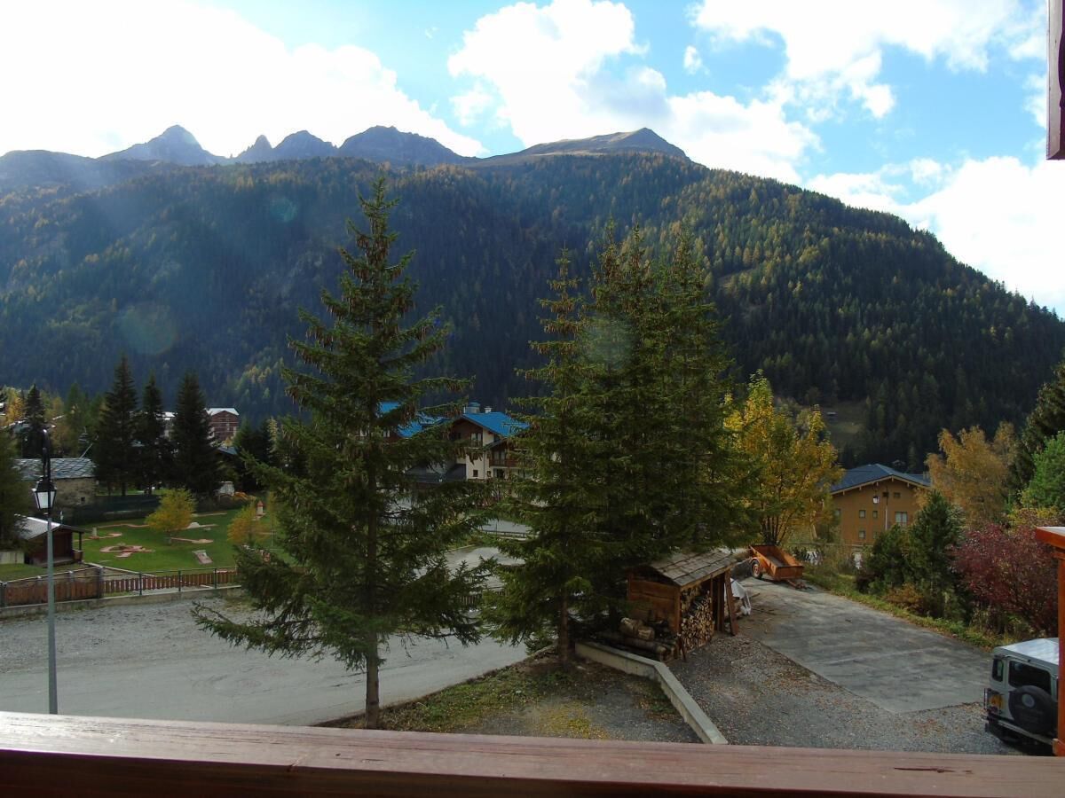 A mountain view with a small building and a parked vehicle in the foreground.