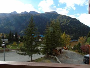 Une vue sur une montagne, avec un petit bâtiment et un véhicule garé au premier plan.