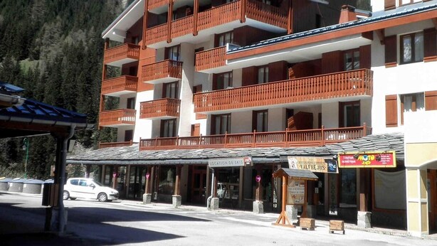 Un hôtel à plusieurs étages doté de balcons, d’un panneau indiquant l’emplacement des pistes de ski et d’un magasin situé à proximité.