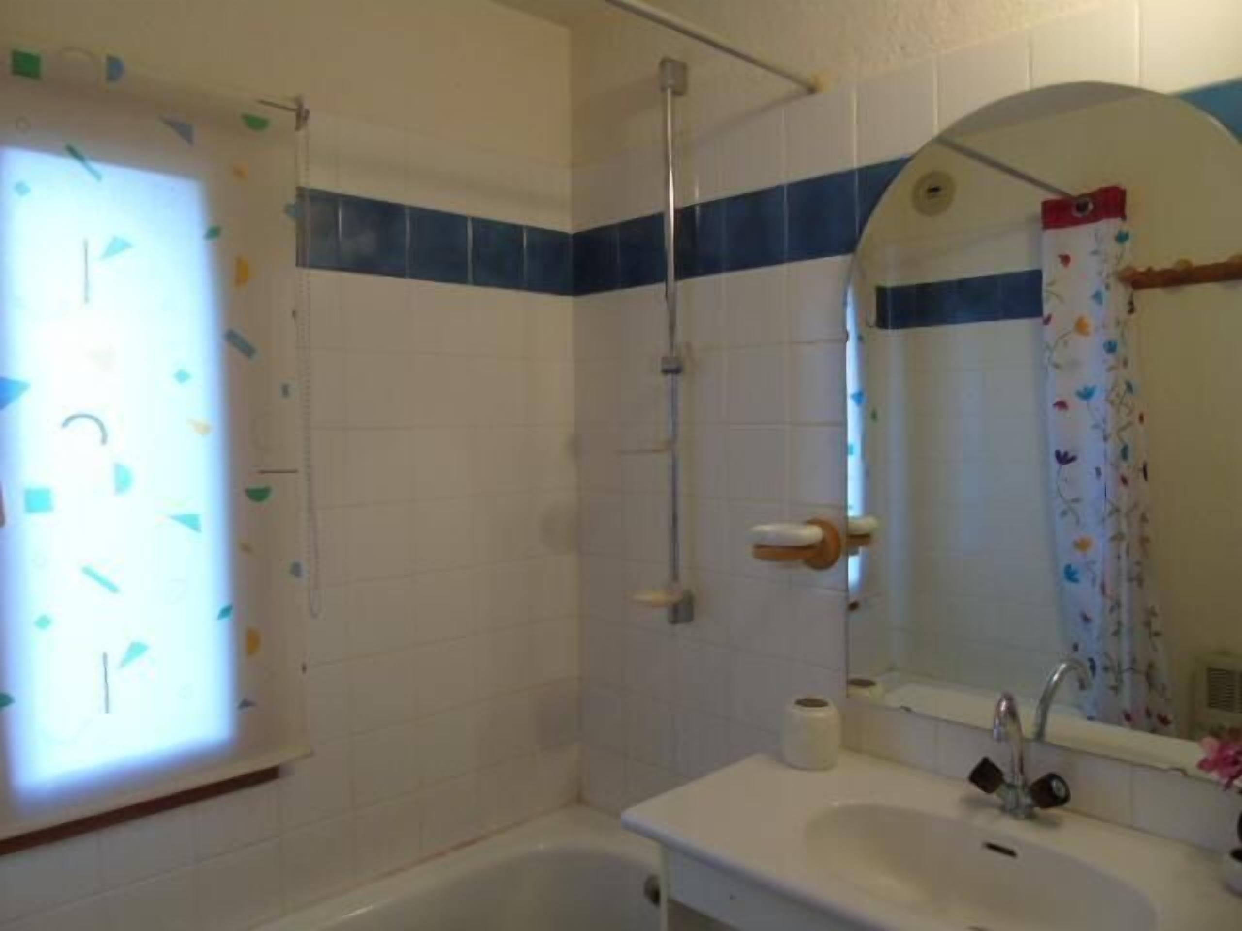 A bathroom with a bathtub, a sink with a mirror, and a shower area.