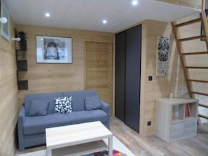 Ein gemütliches Zimmer mit einem grauen Sofa, einem weißen Couchtisch und einem Bücherregal.