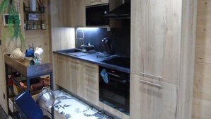 Une cuisine de taille réduite, dotée de meubles en bois, d’un four encastré et d’un évier.