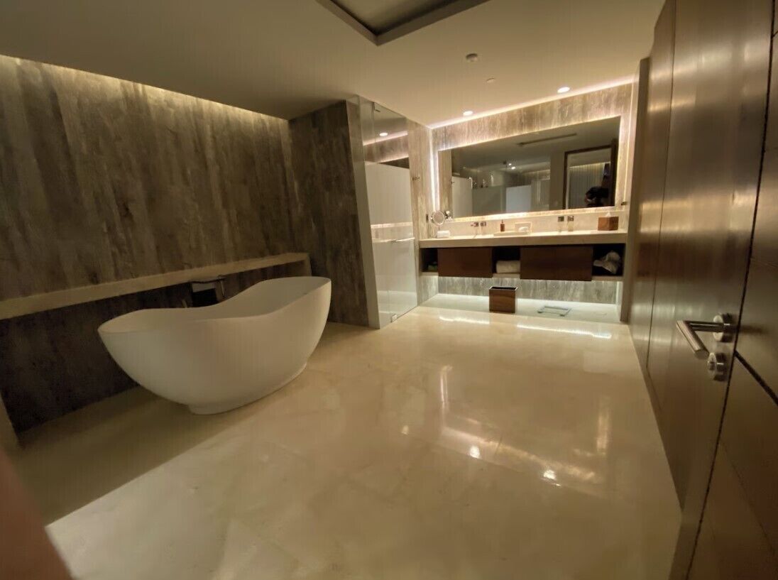Een moderne badkamer met een vrijstaand ligbad, een wastafel met spiegel en een strak, minimalistisch design.