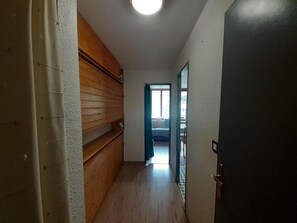 A narrow hallway with wooden paneling on one side and a black door on the other. - 20m from ski lifts, 1st floor, balcony, tv, ski locker, 19m², Valfréjus (Valfréjus)