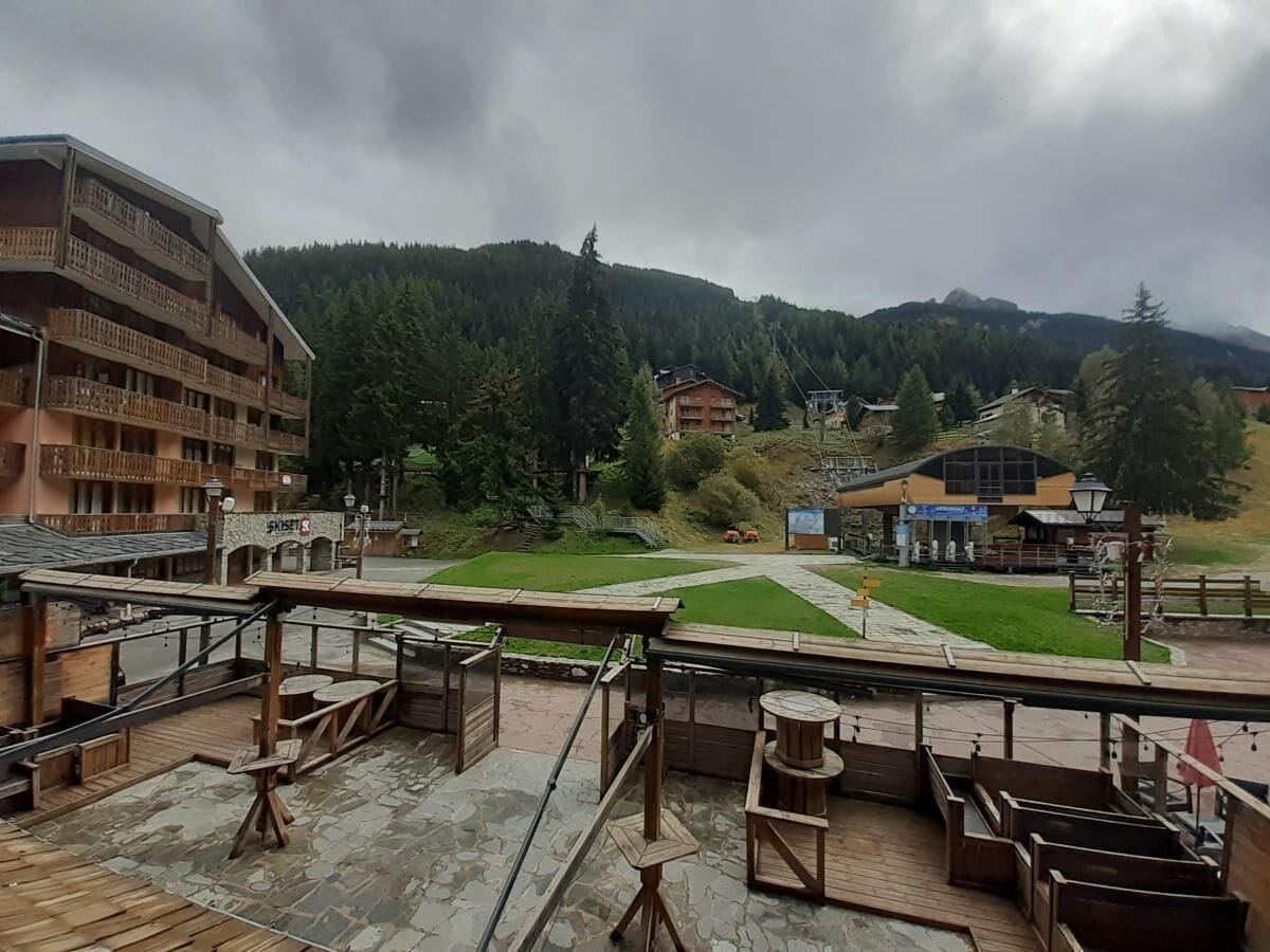 A hotel with a terrace overlooking a mountainous area, featuring a wooden deck and outdoor seating.