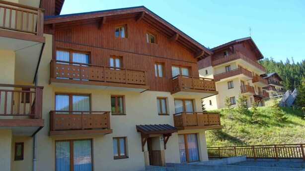 A multi-story building with balconies, a wooden facade, and a sloped roof. - Ground floor, view valley, tv, ski locker, 31m², Valfréjus (Valfréjus)