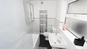 A modern bathroom with a bathtub, toilet, and sink.