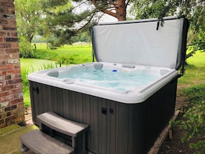 Relax in a serene outdoor setting with a spacious hot tub, accessible via a convenient step.