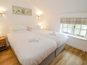 Relax in a spacious room with a large bed, two pillows, and a bedside table with a lamp.