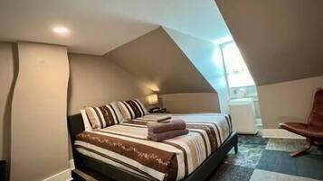 A bedroom with a bed, a nightstand, and a chair.