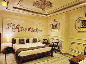 A bedroom with a large bed, bedside tables, a desk, and chairs. - The Hotel Rajputana (Sawai Madhopur)