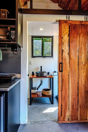A modern kitchen with a wooden door, a window, and a countertop with a microwave and kettle. - Kooteja Anton Valley ËRA (Los Llanitos)