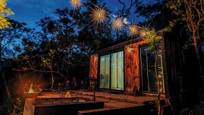 A wooden cabin with a glass door, a fire pit, and string lights. - Kooteja Anton Valley ËRA (Los Llanitos)