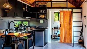 A modern kitchen with a central island, bar stools, and a wooden door leading to another room. - Kooteja Anton Valley ËRA (Los Llanitos)