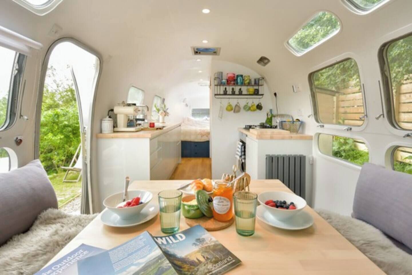A cozy interior of a camper van with a dining area, kitchenette, and a small bed.