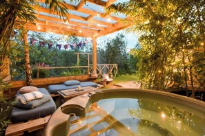 Un área de hidromasaje al aire libre con asientos de madera y una pérgola.