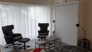 Et moderne værelse med to sorte kontorstole, et lille bord, et garderobeskab og en lampe.