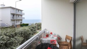 En balkon med bord, stole og en lille skraldespand.