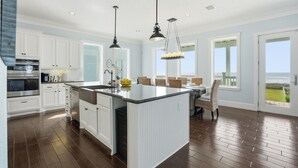 A spacious kitchen with white cabinetry, a central island, and a dining area with a view.