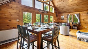 L’intérieur d’un chalet en bois, avec une table à manger dressée pour quatre personnes, un canapé et une pancarte indiquant « Bethel, Maine ».