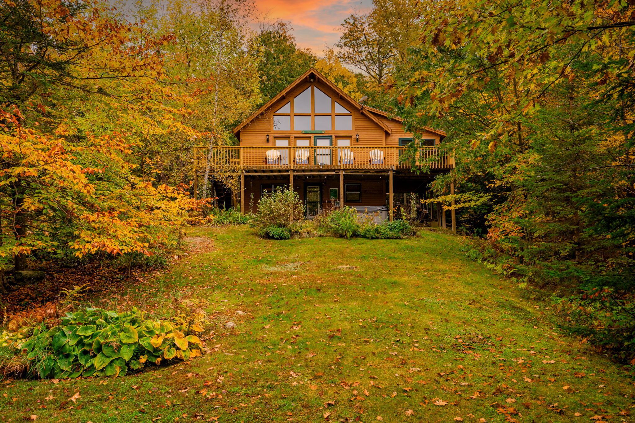 A wooden cabin with a balcony, surrounded by autumn foliage.